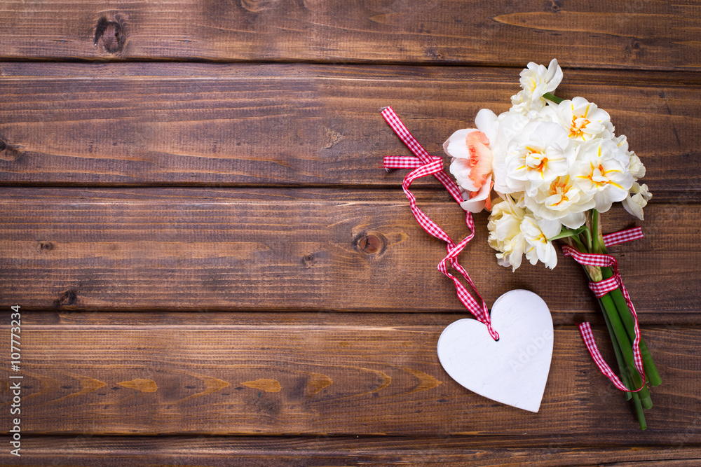 Yellow narcissus flowers and decorative heart on brown wooden Yellow narcissus flowers and decorative heart on brown wooden