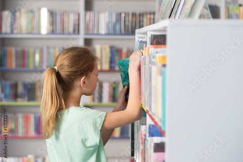Cute girl reading book in library 

