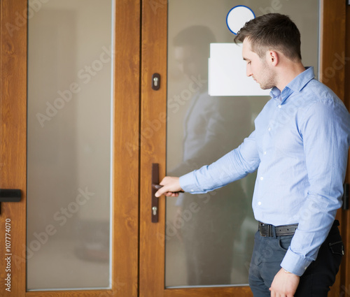 Corporate man opening his office door