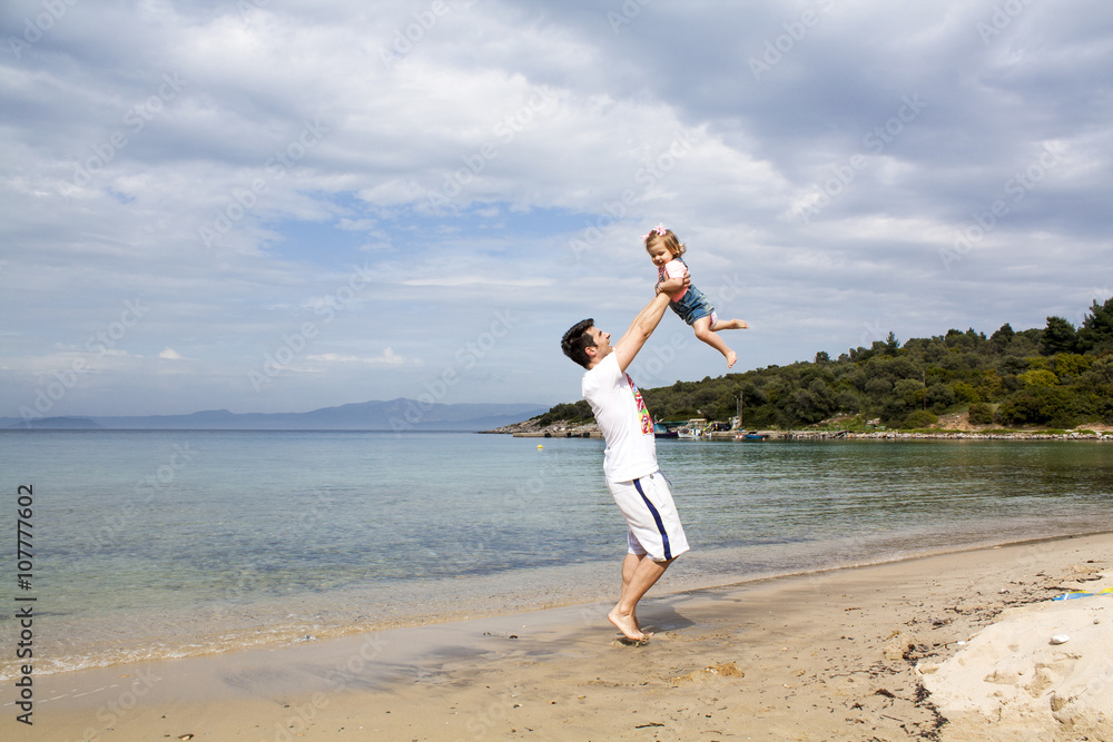 Healthy father and daughter playing together at the beach carefree happy fun smiling lifestyle. Father and Daughter Having Fun at the Beach