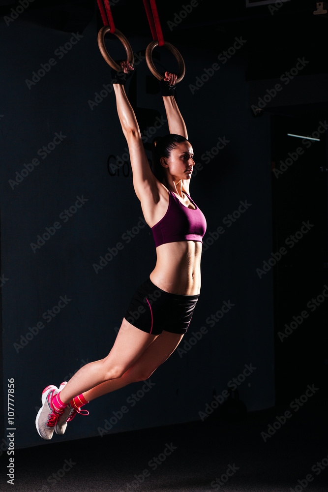 Sporty woman using gymnastic rings/ Sporty women in a gym exercising with gymnastic  rings Stock Photo