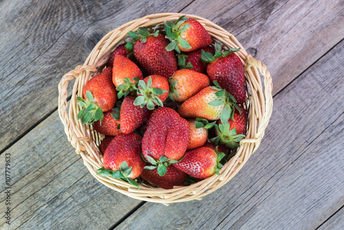 Fresh, ripe strawberries in a basket on a wooden background. photo