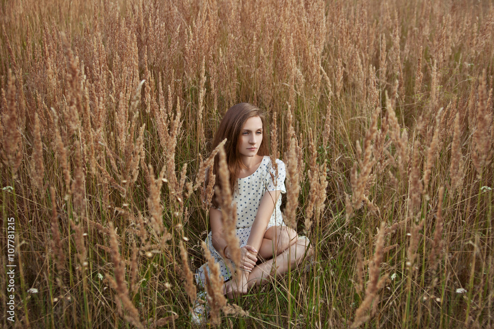 beautiful young woman sitting in grass