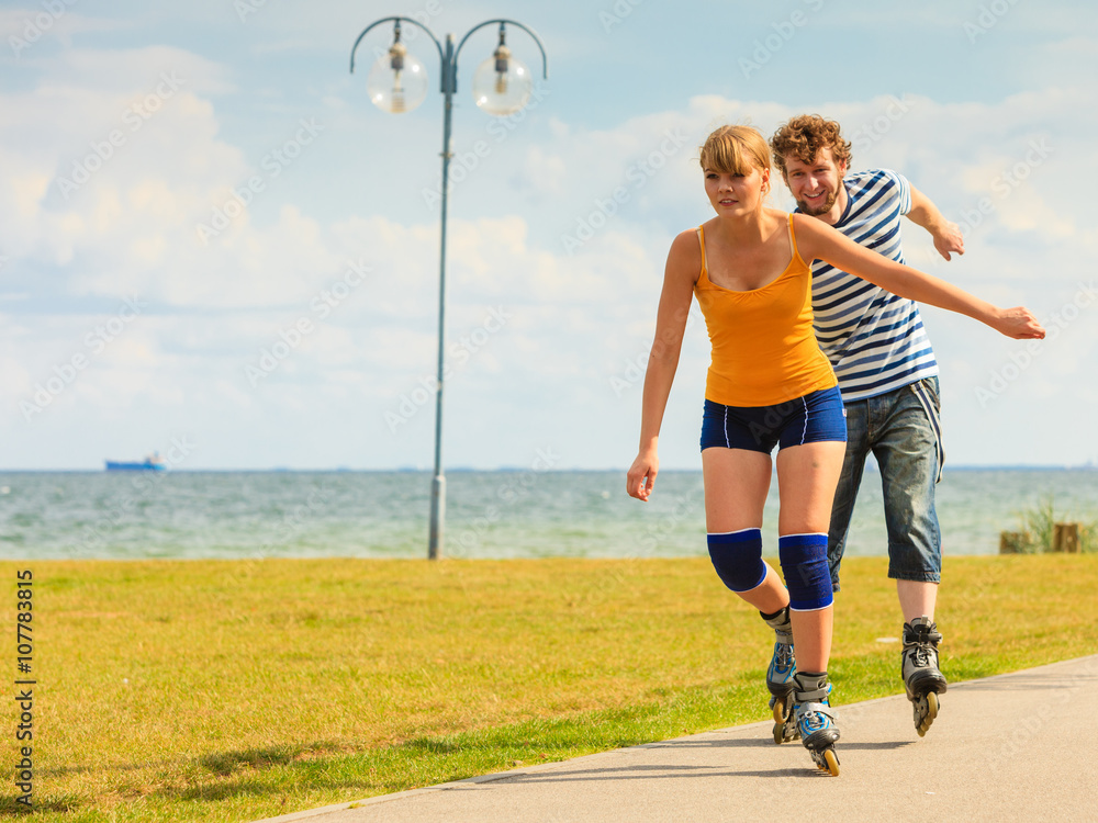 Fototapeta premium Young couple on roller skates riding outdoors
