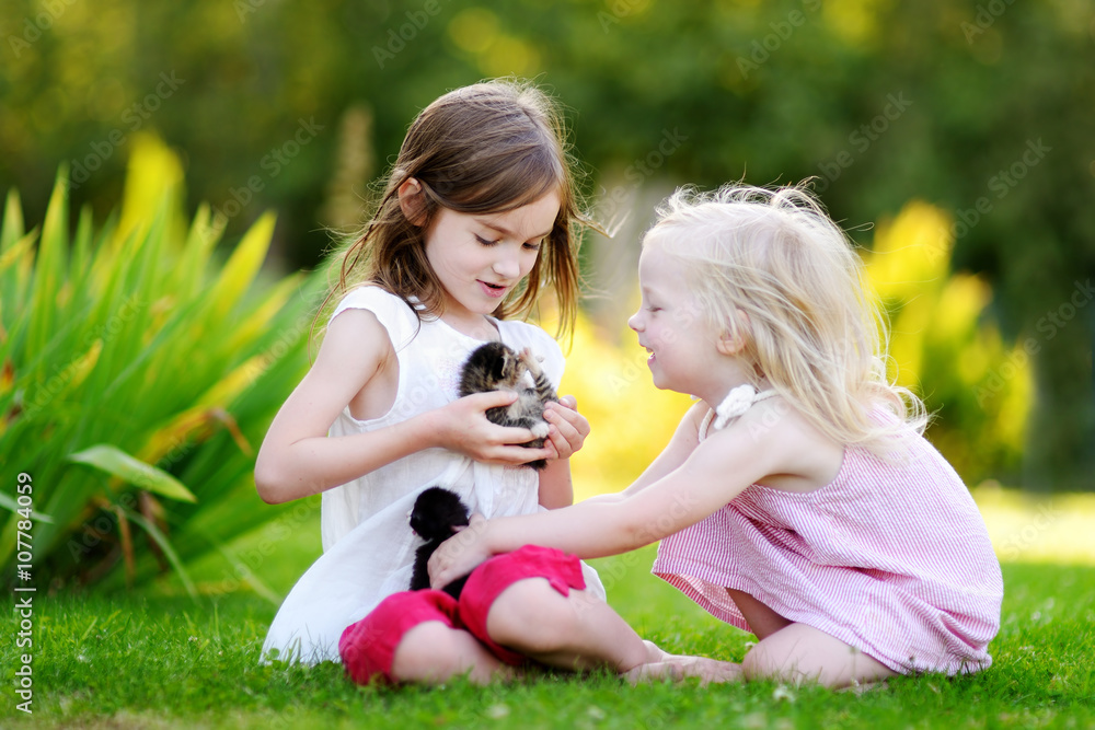Two adorable little sisters playing with small newborn kittens Two adorable little sisters playing with small newborn kittens