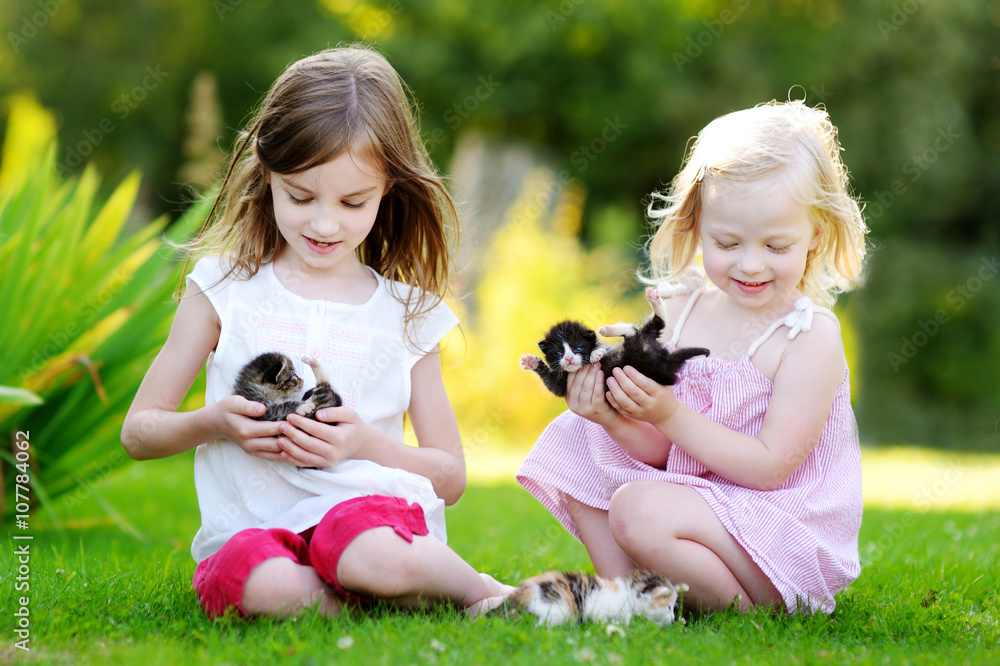 Two adorable little sisters playing with small newborn kittens Two adorable little sisters playing with small newborn kittens