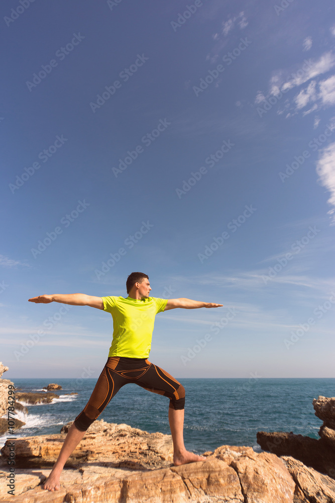 young man doing yoga exercises on the beach.