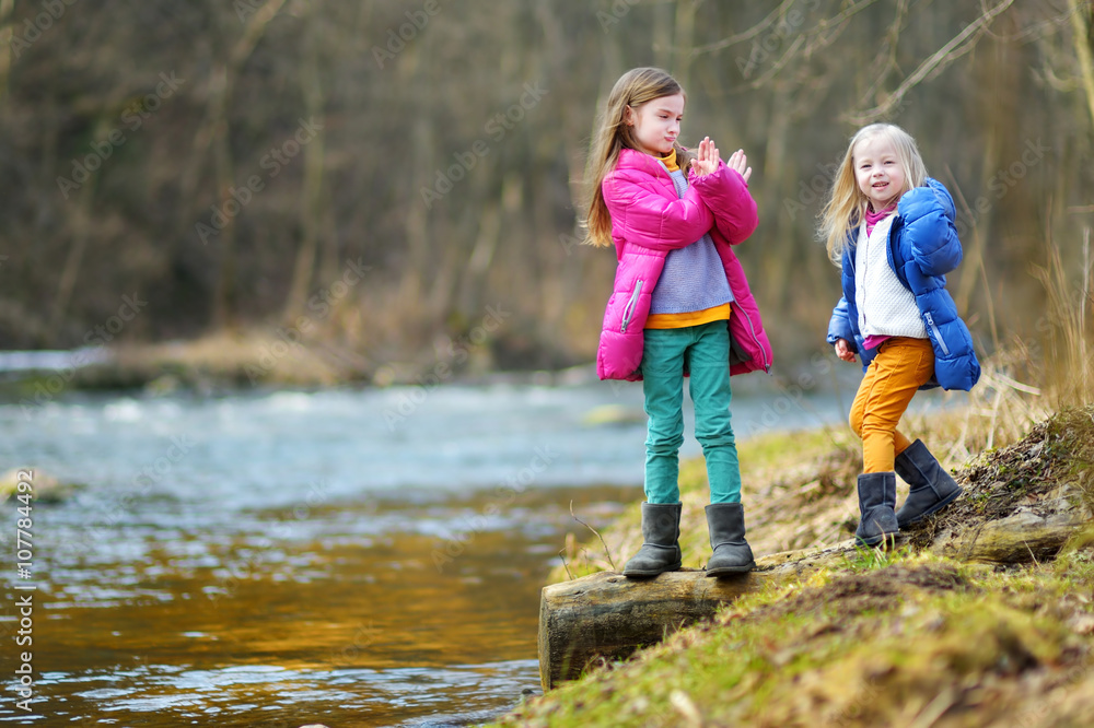 Two cute little sisters having fun by a river Two cute little sisters having fun by a river