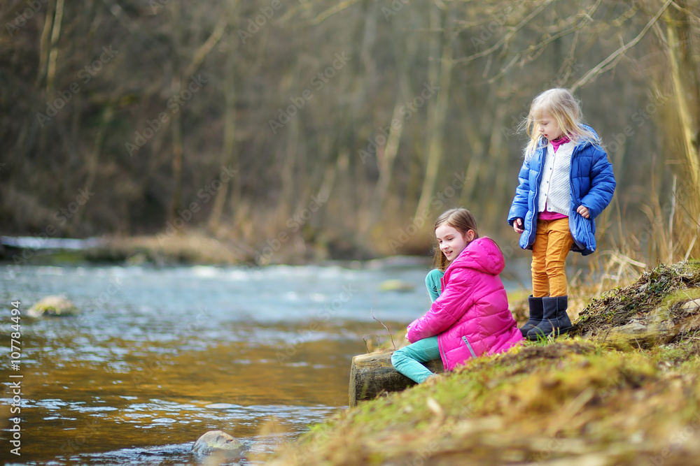 Two cute little sisters having fun by a river Two cute little sisters having fun by a river