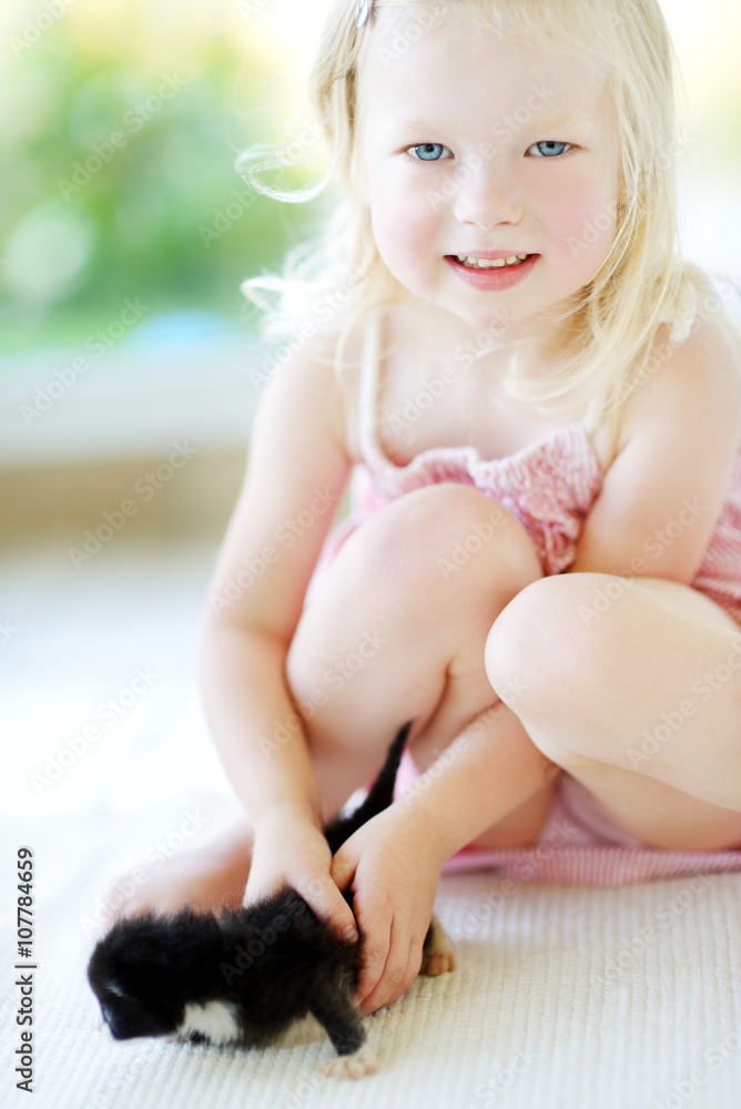 Obraz premium Adorable little girl playing with small kitten