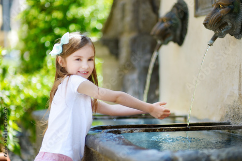 Adorable little girl playing with a drinking water fountain