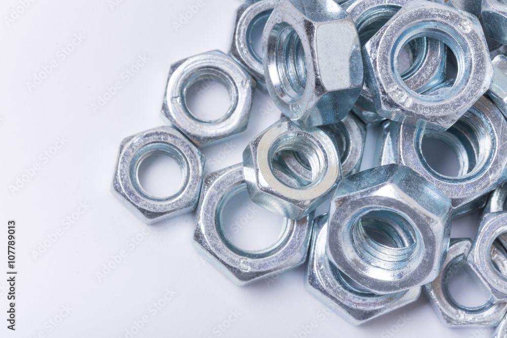 Macro image of pile of grey metal nuts over white background Macro image of pile of grey metal nuts over white background