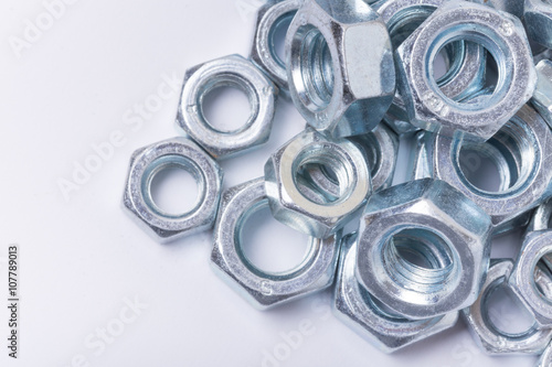 Macro image of pile of grey metal nuts over white background