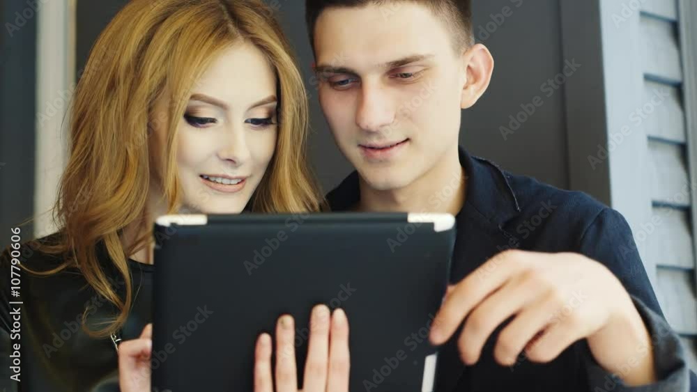 A young couple enjoys the tablet in cafe A young couple enjoys the tablet in cafe