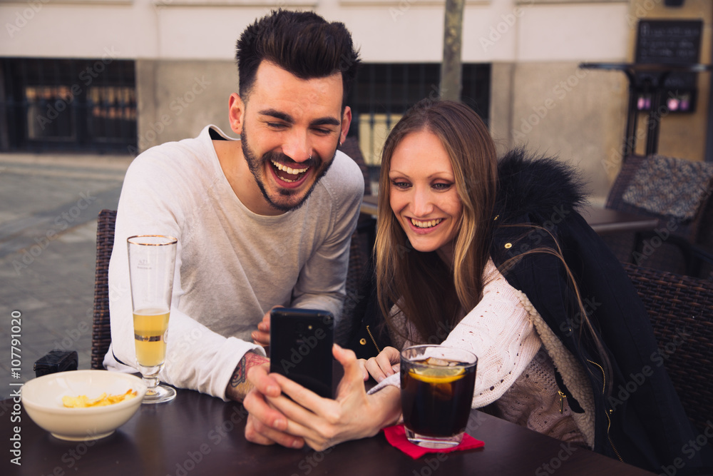 Couple using digital phone iphone and laughing in a terrace