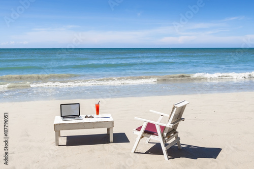 Working online from a tropical beach with laptop computer
