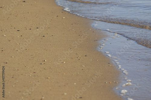 Morning beach with tidal bore and smooth sand with scattering of little stones