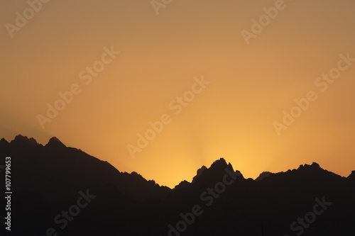 Mountain sunset with orange sky and ridge silhouette