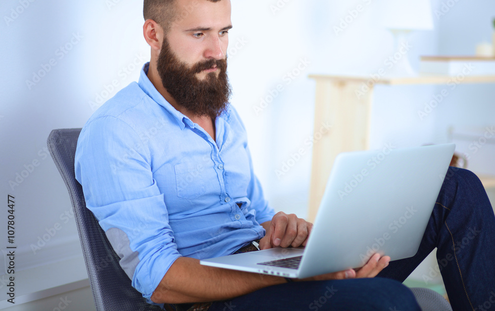 Handsome young man sitting and working on laptop computer Handsome young man sitting and working on laptop computer