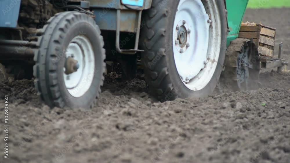 Agricultural tractor plows soil and plantings of agricultural cultures, blurred background, filmed on telephoto lens Agricultural tractor plows soil and plantings of agricultural cultures, blurred background, filmed on telephoto lens