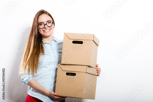 Happy woman moving into house carrying boxes. © Voyagerix