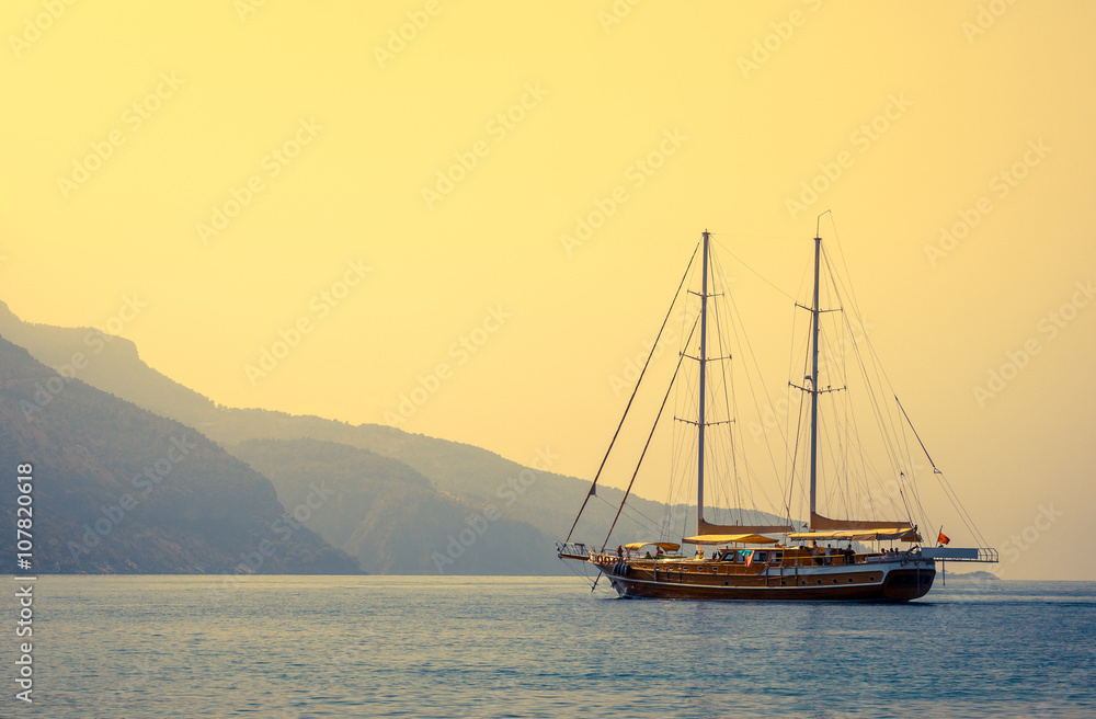 Marine landscape with sailboat at sunset.