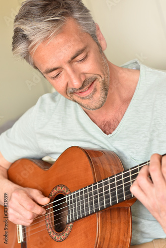 Man playing acoustic guitar at home
