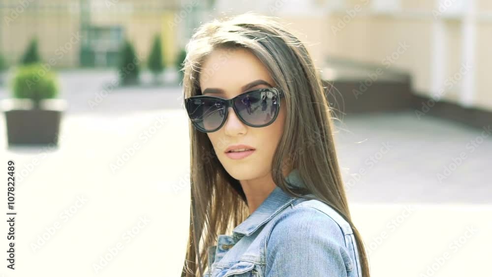 Sexy girl in sunglasses looking on camera on sunshine background. Slowly Sexy girl in sunglasses looking on camera on sunshine background. Slowly