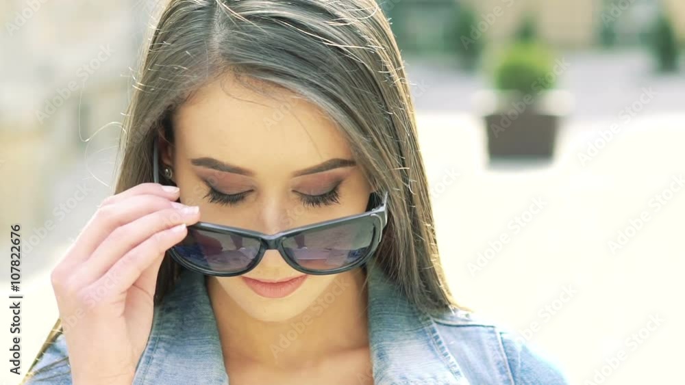 Beautiful girl taking off sunglasses and smiling to camera. Slowly Beautiful girl taking off sunglasses and smiling to camera. Slowly