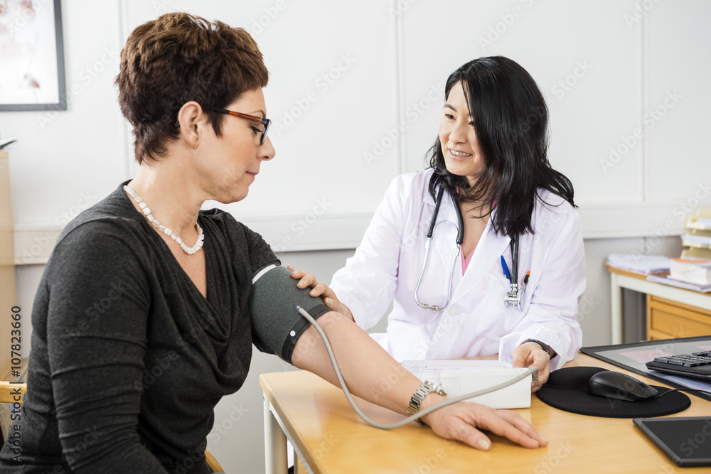 Doctor Examining Female Patient's Blood Pressure