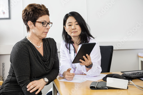 Serious Doctor Showing Digital Tablet To Patient