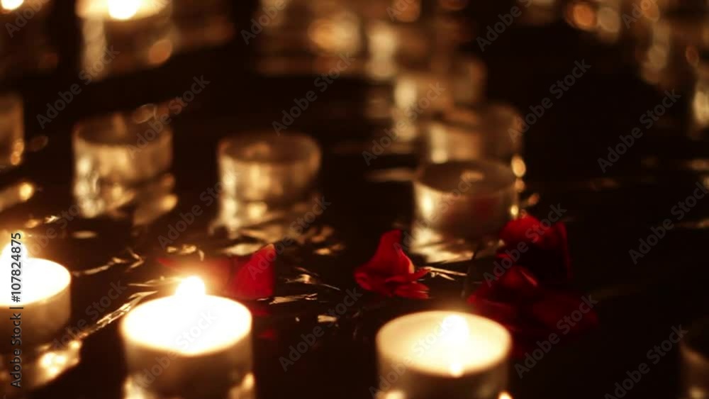 Red Flower Petals Fall Down Softly Near Small Burning Candles Red Flower Petals Fall Down Softly Near Small Burning Candles