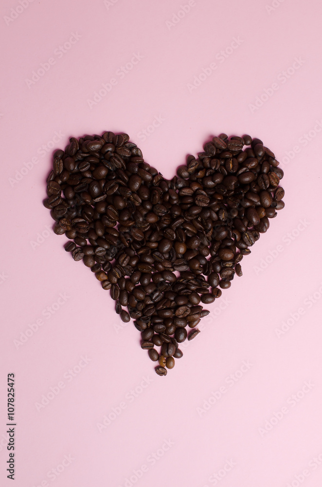 coffee beans as a heart on a pink background from above coffee beans as a heart on a pink background from above