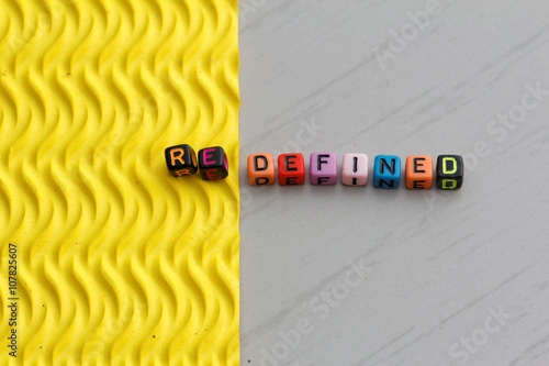 Plastic alphabet block arranged to form word REDEFINED. Two different texture represent the word redefined.
