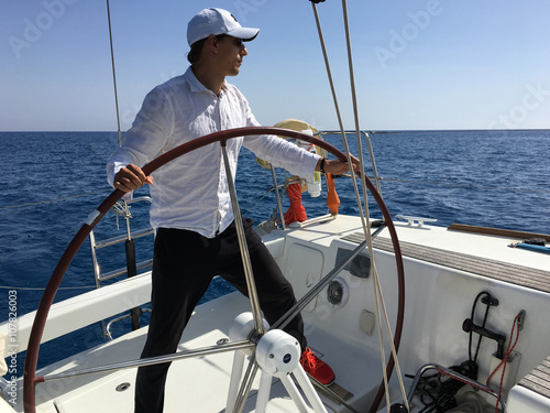 Young man sailing yacht steering wheel vacation