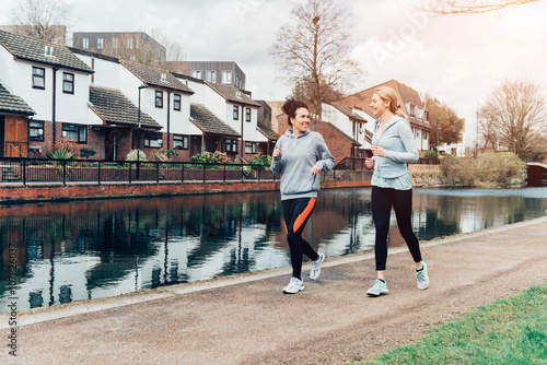  Two young female running together in city environment.