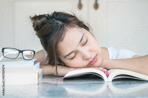 Woman sleeping after she tired for reading with a book on marble table in front of house