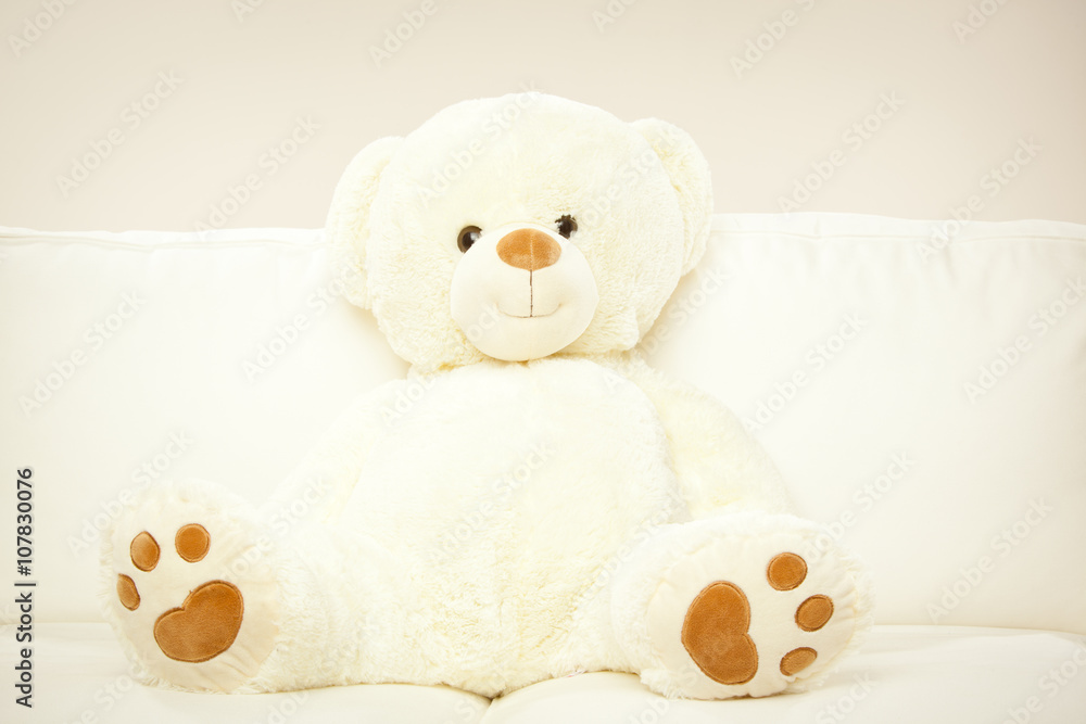 blonde female child play with her white teddy bear in a bed