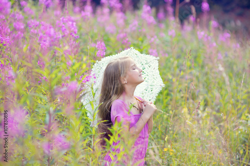 Young beautiful model girl wearing pink dress dream with lace umbrella in blossom flowers field