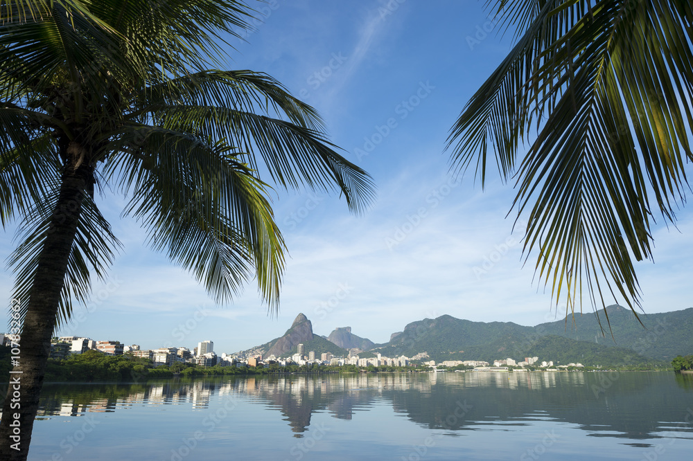 Obraz premium Scenic skyline morning view of Lagoa Rodrigo de Freitas lagoon in Rio de Janeiro Brazil with Ipanema and Leblon reflecting between palm trees on the calm horizon 