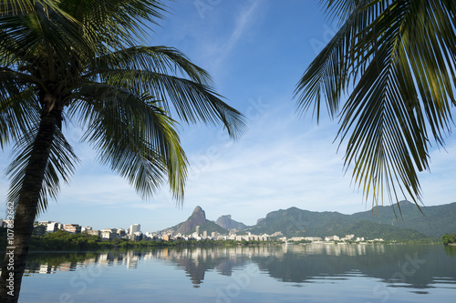 Scenic skyline morning view of Lagoa Rodrigo de Freitas lagoon in Rio de Janeiro Brazil with Ipanema and Leblon reflecting between palm trees on the calm horizon  © lazyllama