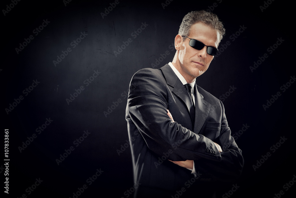 businessman with black suit and sunglasses isolated on black businessman with black suit and sunglasses isolated on black