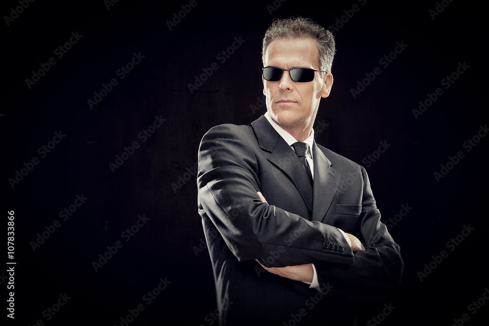 Fototapeta premium businessman with black suit and sunglasses isolated on black