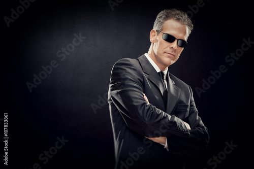 businessman with black suit and sunglasses isolated on black