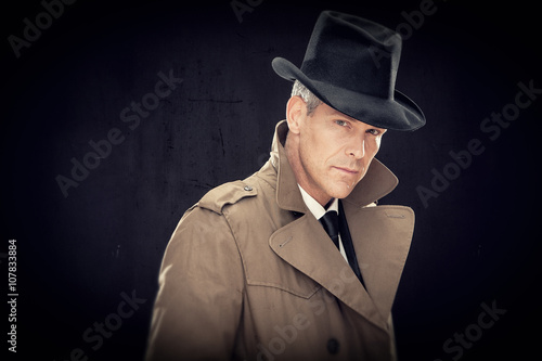 handsome businessman with hat and raincoat isolated on black