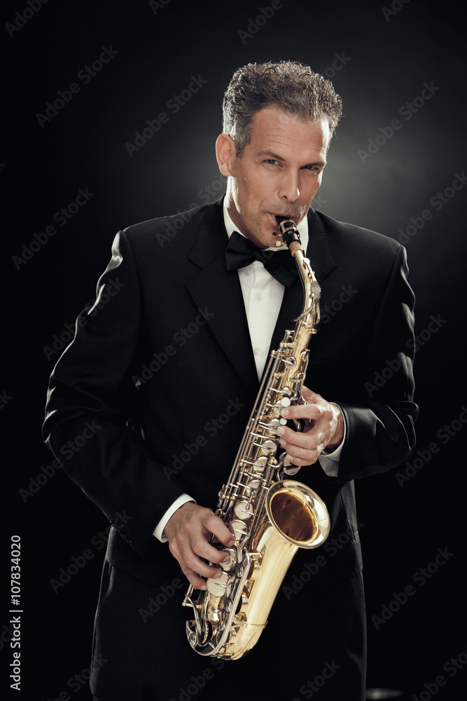 Naklejka premium handsome businessman play saxophone isolated on black