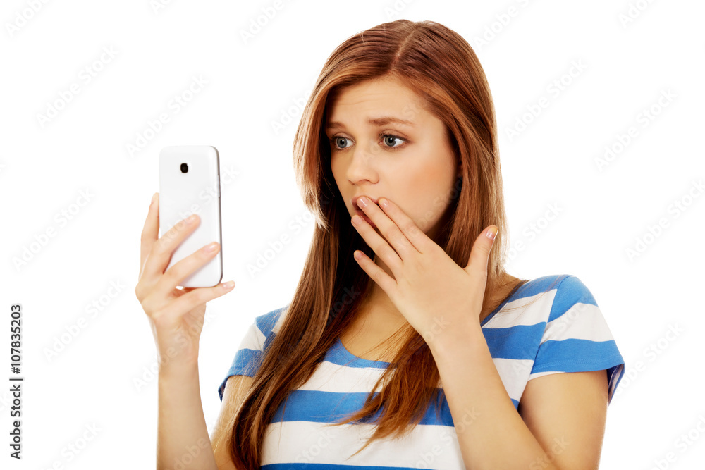 Teenage shocked woman reading a message on mobile phone Teenage shocked woman reading a message on mobile phone