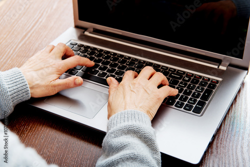 Senior sitting at table and using laptop photo