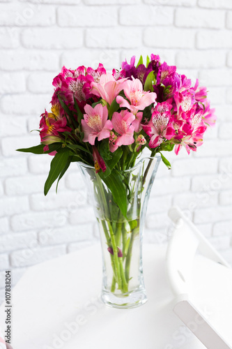 Vase full of colorful flowers on table