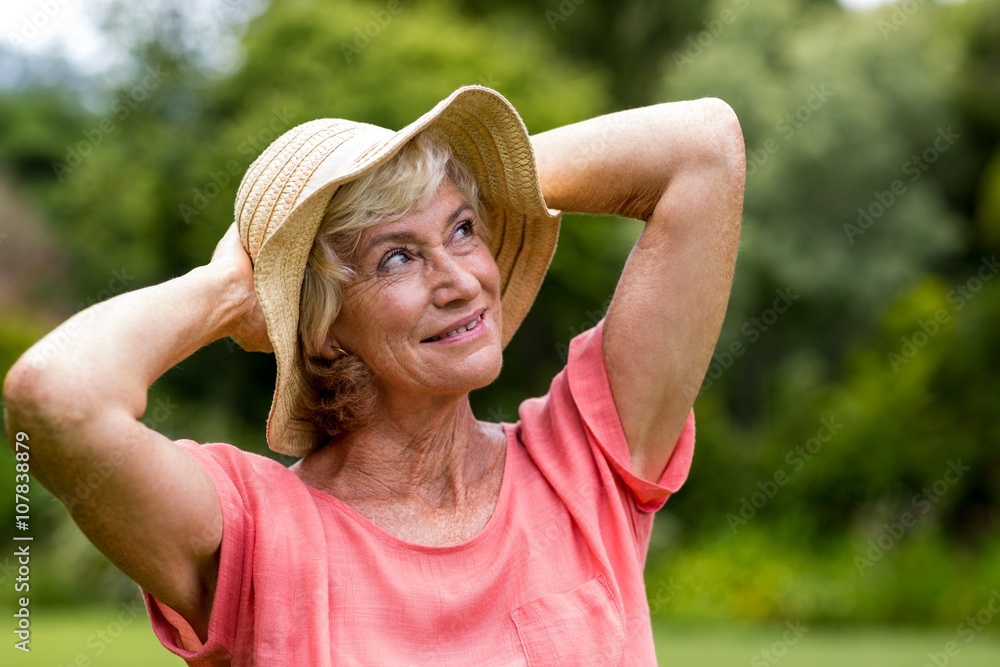 Senior woman in hat standing in yard 